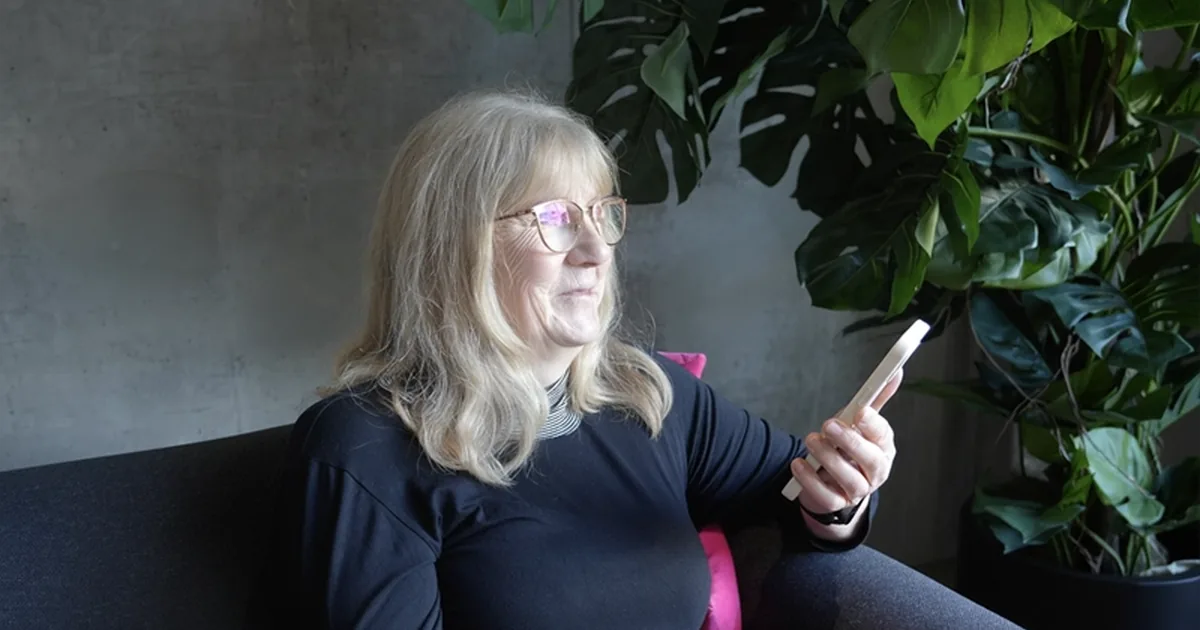 Ältere Frau schaut lächelnd auf ihr Smartphone